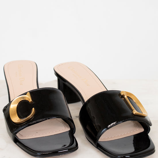 Black sandals with gold details on a white background