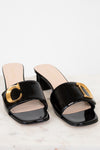 Black sandals with gold details on a white background