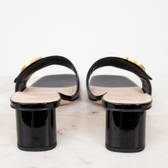 Black sandals with beige soles on a white marble surface