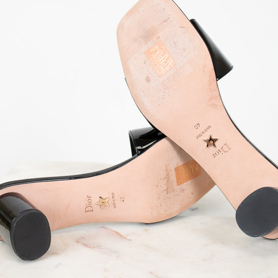 Soles of high-heeled shoes with visible brand names on a light background