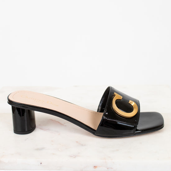 Black sandal with a gold 'C' design on a white background