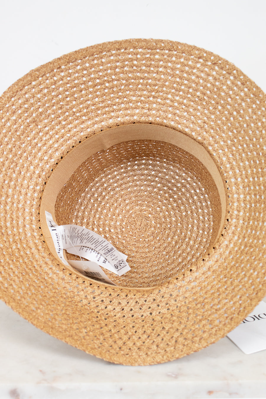 Woven straw hat with a visible brand label on a white background