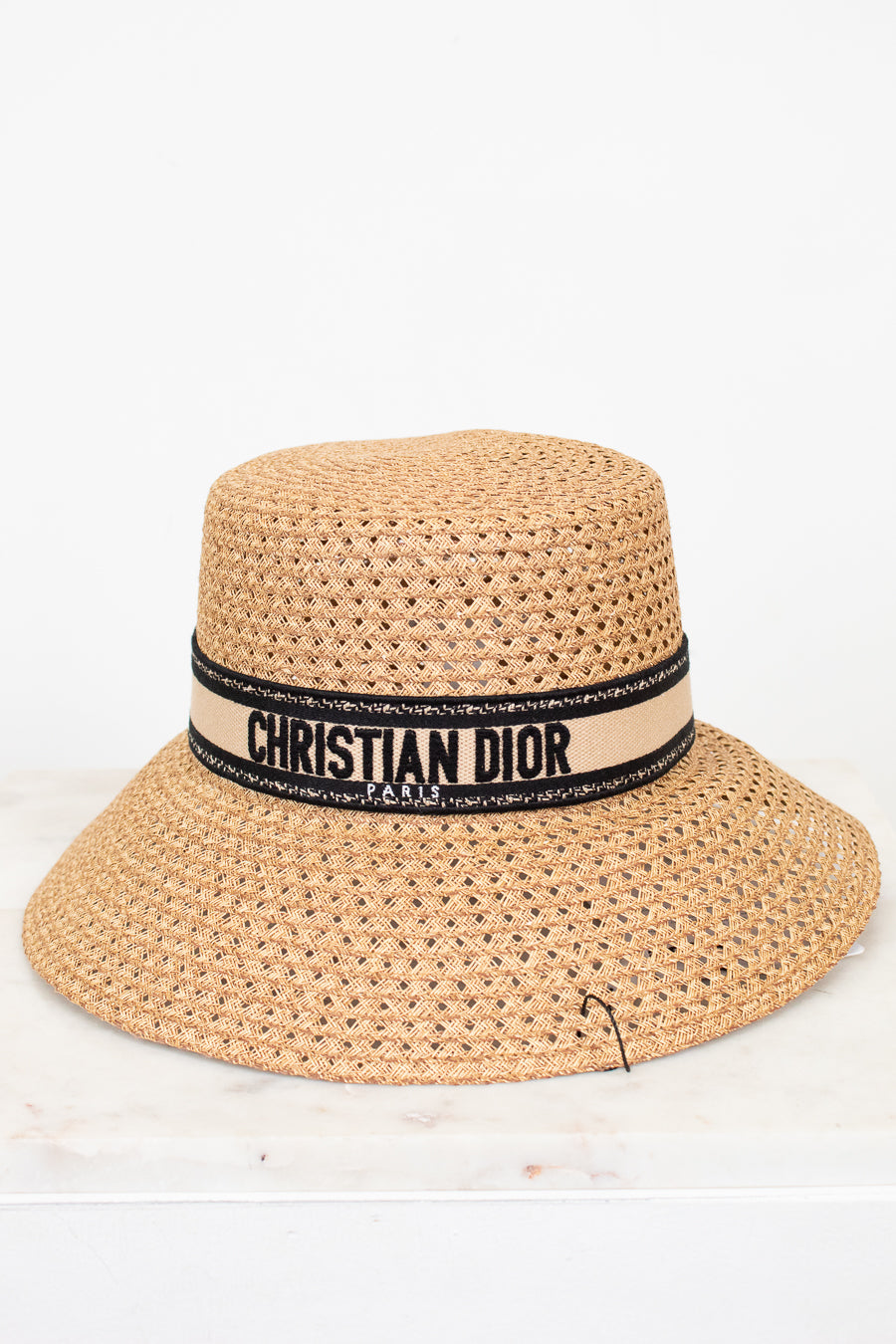 Beige straw hat with Christian Dior band on a white background