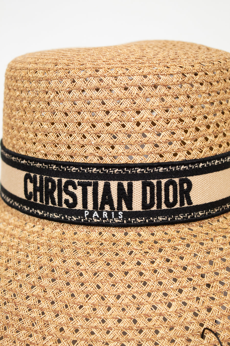 Woven straw hat with a Christian Dior band on a white background