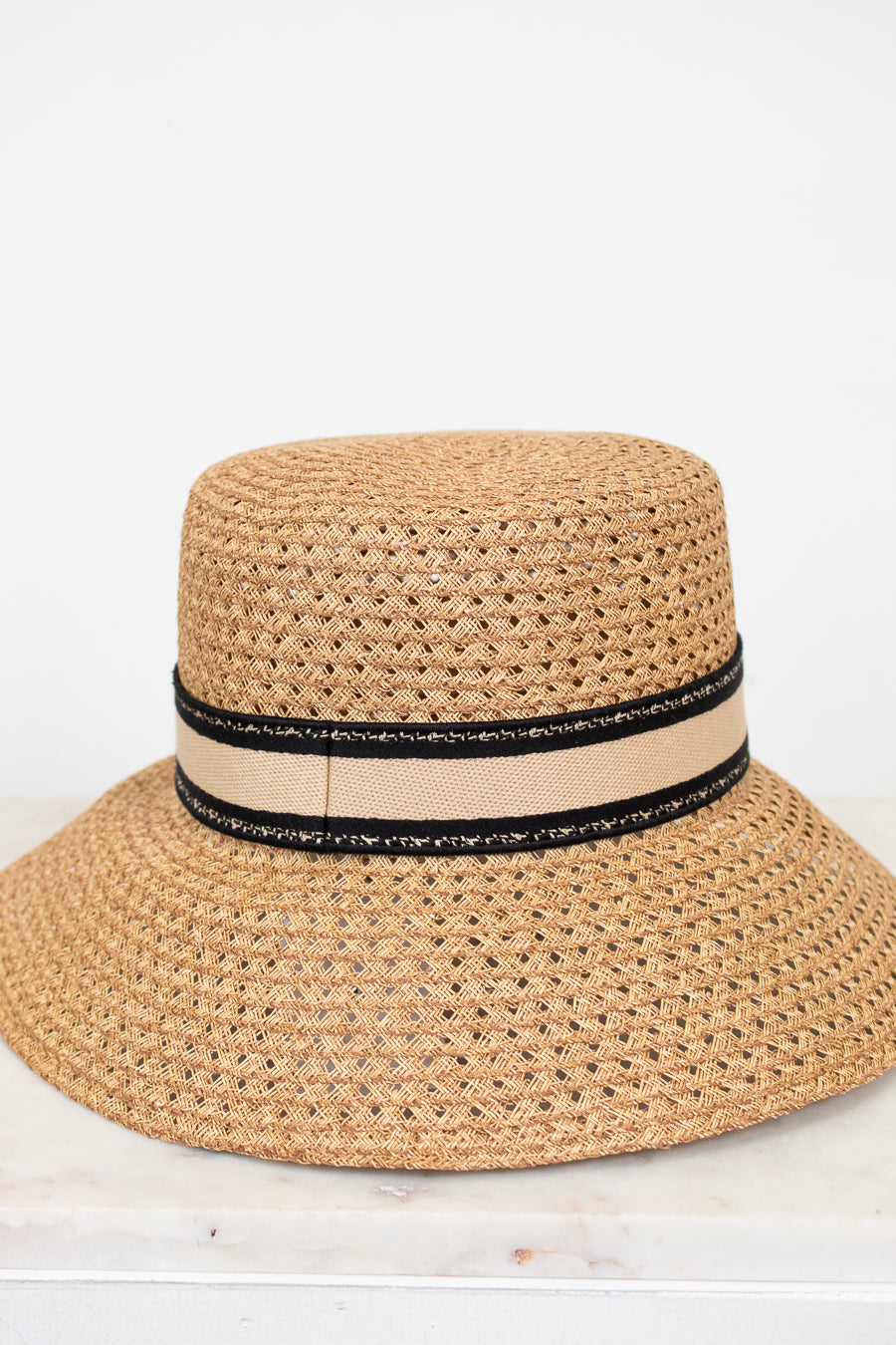 Beige straw hat with a black band on a white background