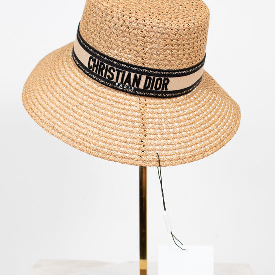 Beige straw hat with Christian Dior band on a mannequin head against a white background