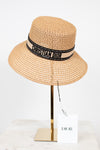 Beige straw hat with Christian Dior band on a mannequin head against a white background