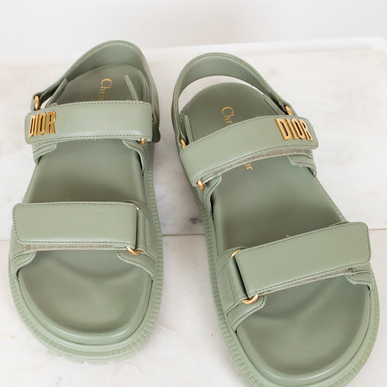 Pair of green sandals with gold accents on a white background