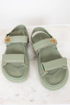 Pair of green sandals with gold accents on a white background