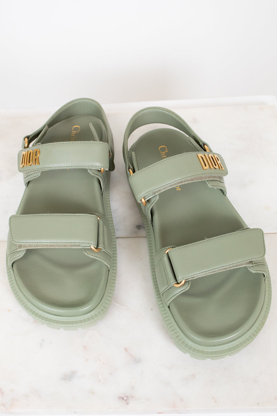 Pair of green sandals with gold accents on a white background