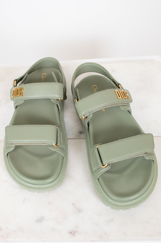 Pair of green sandals with gold accents on a white background