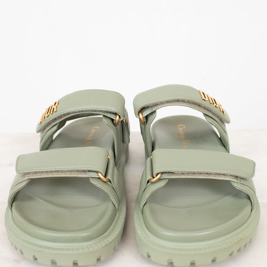 Pair of green sandals with gold accents on a white background