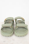 Pair of green sandals with gold accents on a white background