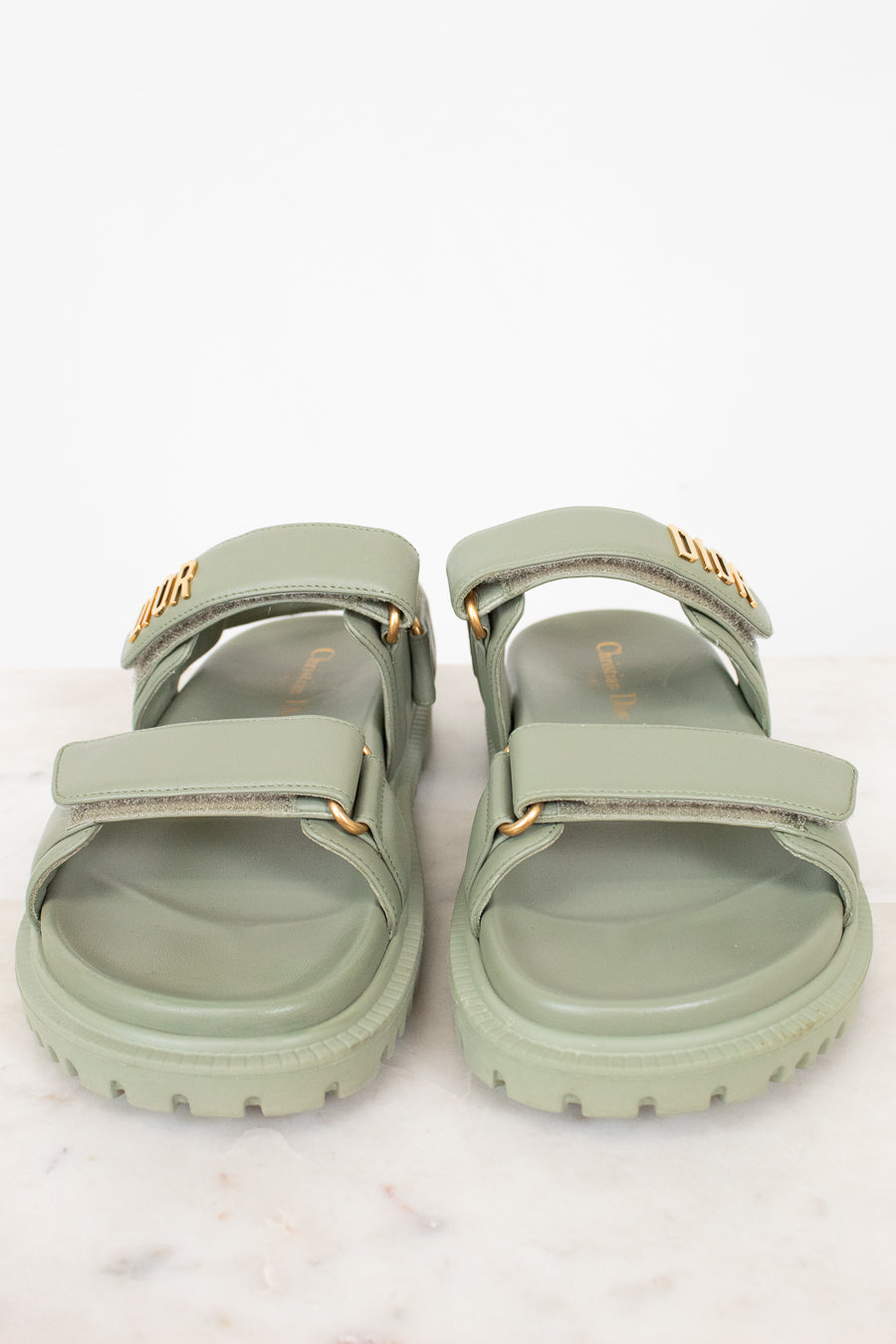 Pair of green sandals with gold accents on a white background