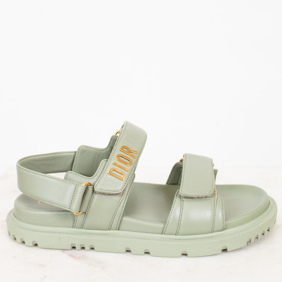 Green sandal with 'Dior' logo on a white background