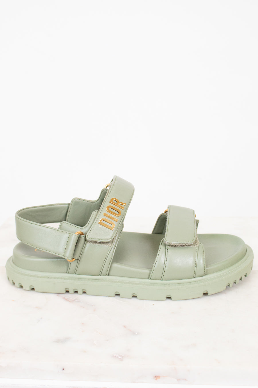 Green sandal with 'Dior' logo on a white background