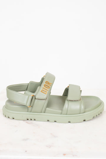 Green sandal with 'Dior' logo on a white background