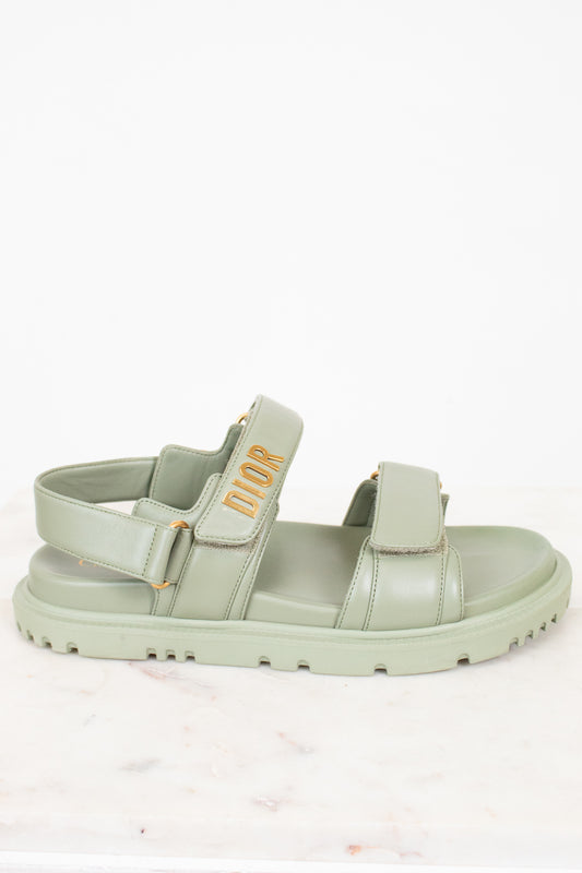 Green sandal with 'Dior' logo on a white background