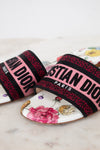 Floral flat sandals with Christian Dior in pink and black woven into toe strap on marble background