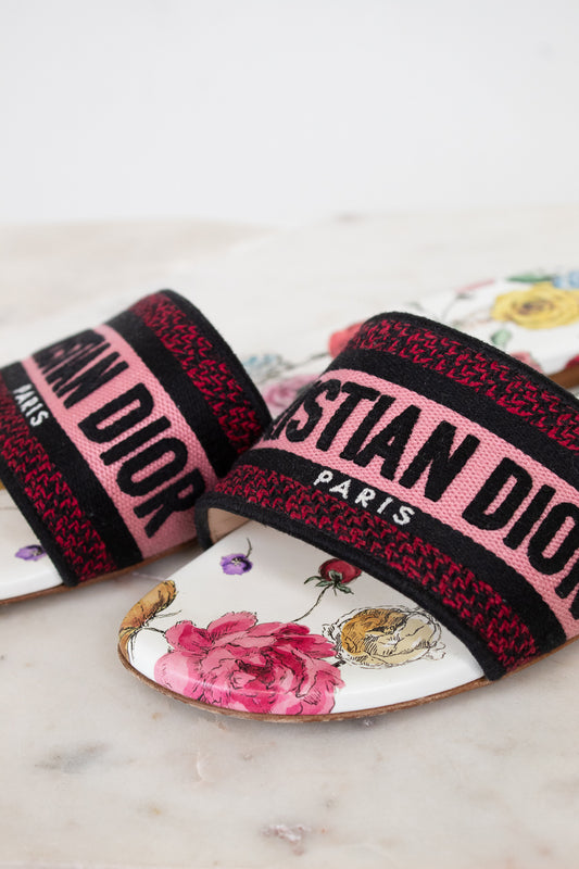 Floral flat sandals with Christian Dior in pink and black woven into toe strap on marble background
