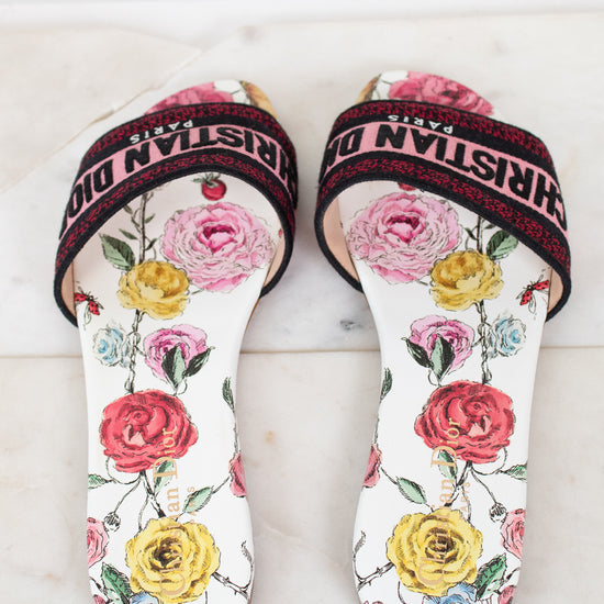Floral flat sandals with Christian Dior in pink and black woven into toe strap on marble background