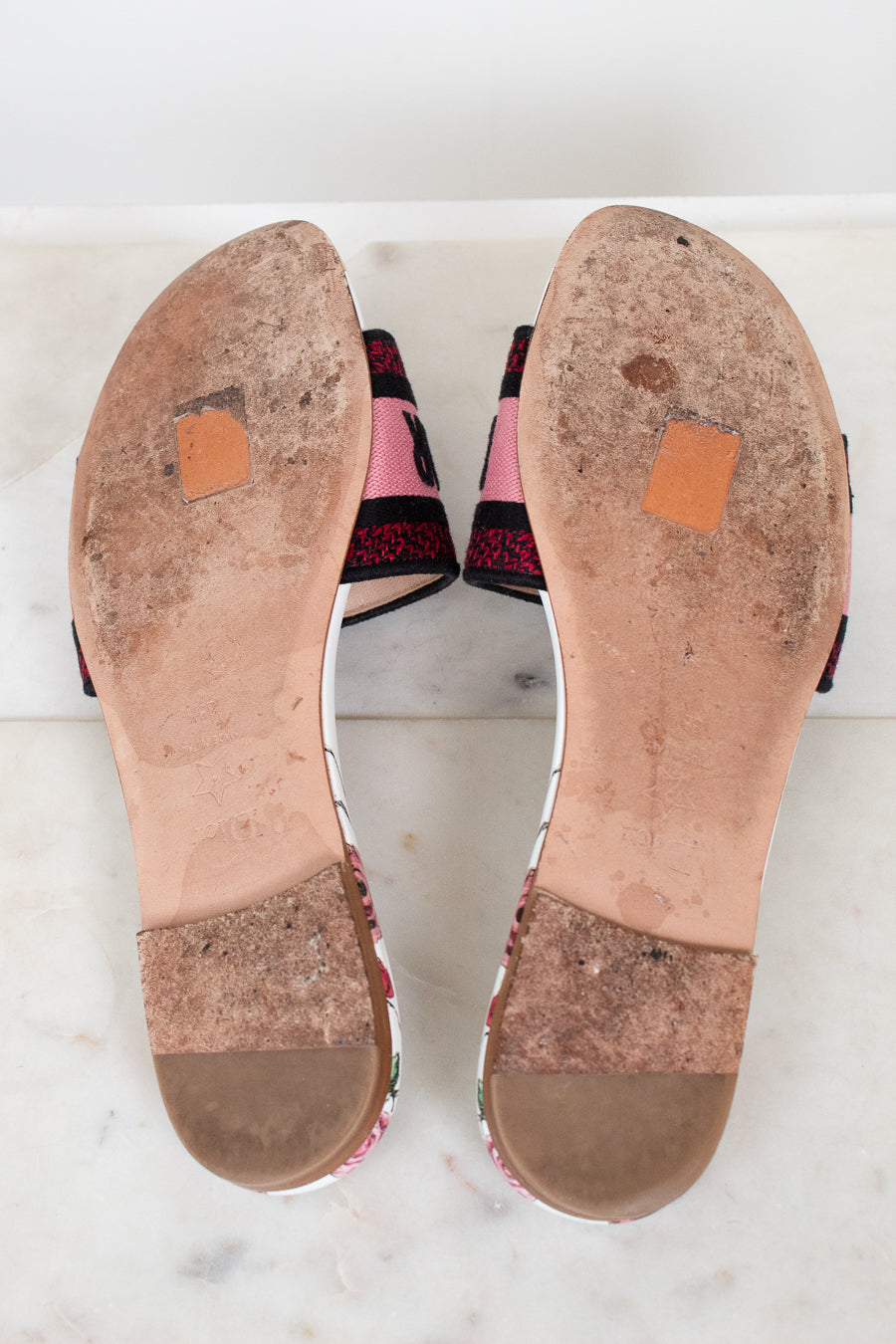 Bottom view of flat sandals with white marble background