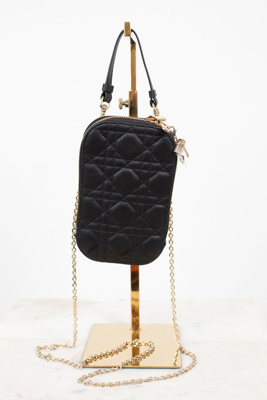 Black quilted pouch case with gold chain on a white background