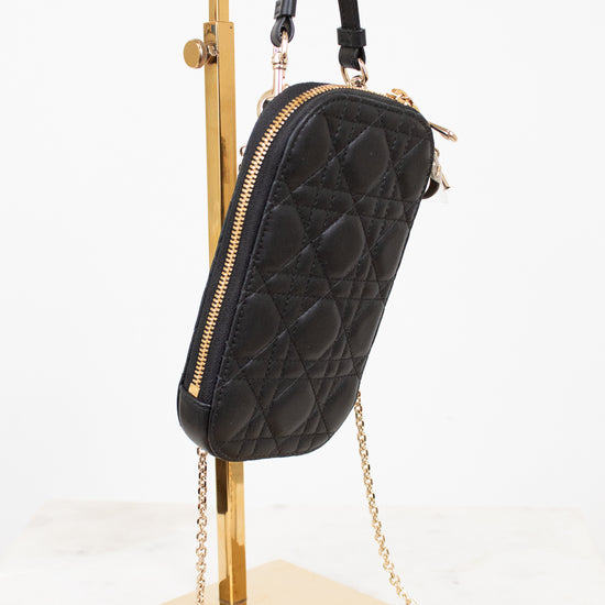 Black quilted handbag with gold chain on a stand against a white background