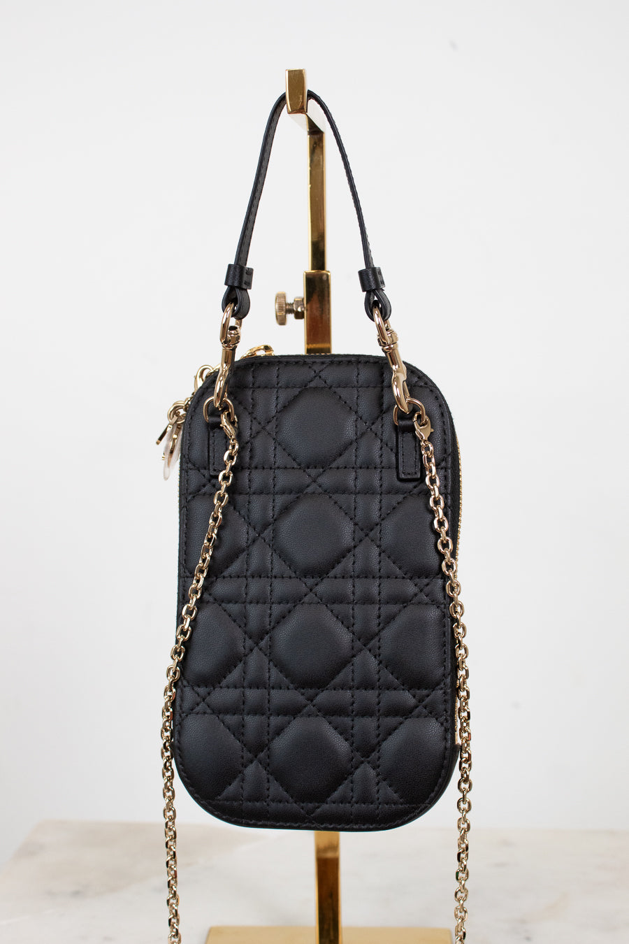 Black quilted handbag with gold chain strap on a white background