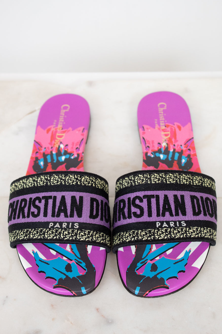 Purple Christian Dior slides with colorful design on a white and marble background