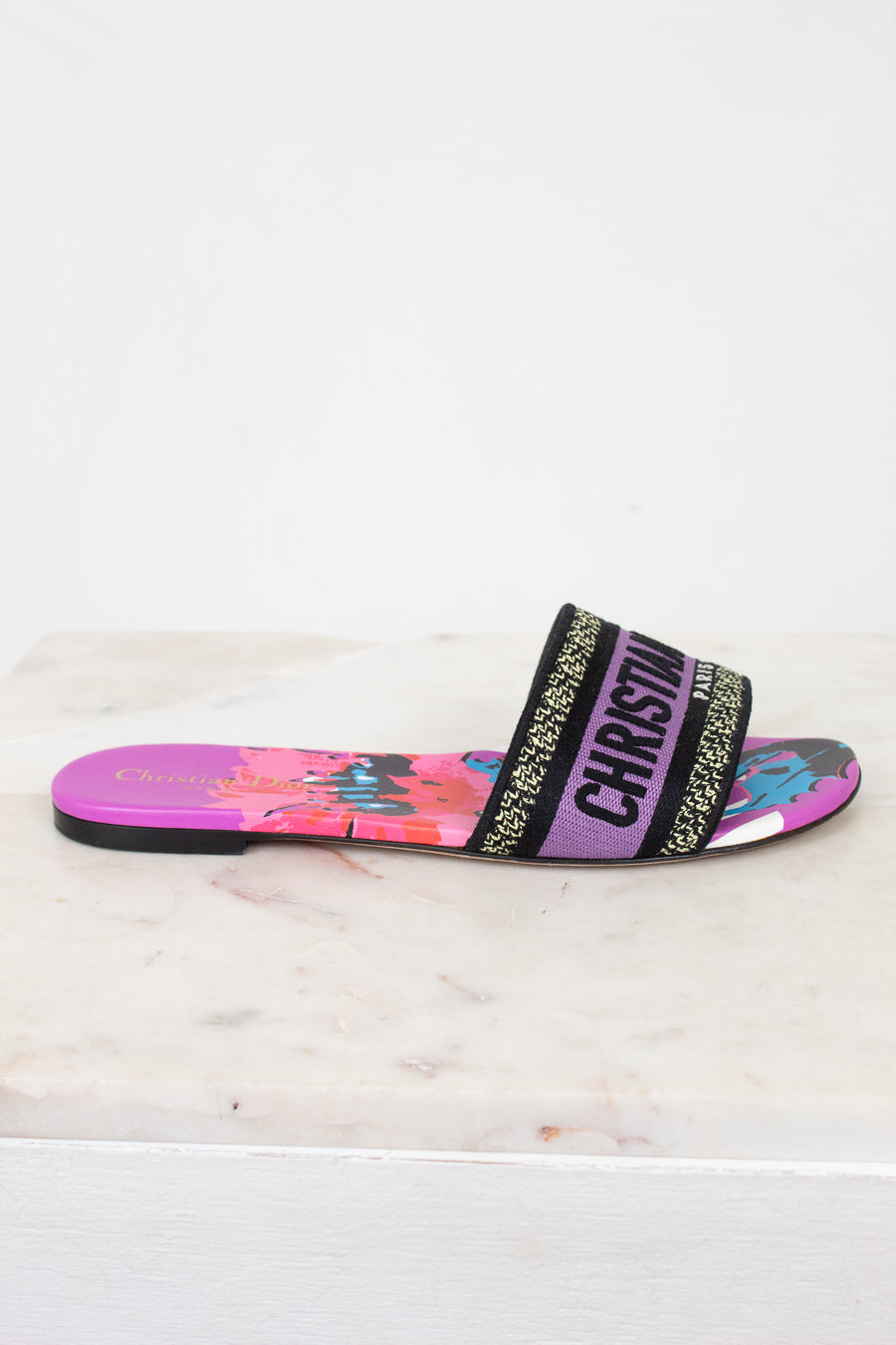 Colorful slide sandal with floral design on a white marble surface
