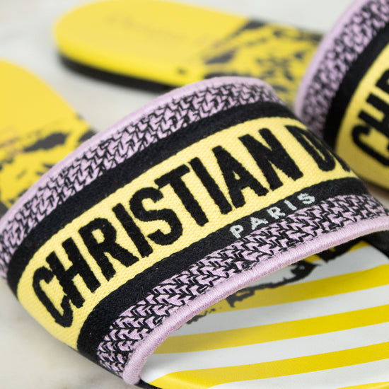Close up of Christian Dior slides with yellow and  black  with white striped pattern on a marble background