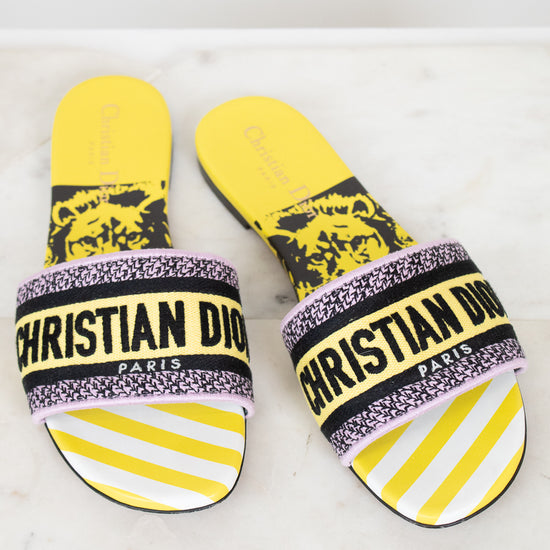 Pair of Christian Dior slides with yellow and  black  with white striped pattern on a light background