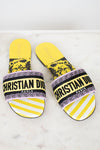 Pair of Christian Dior slides with yellow and  black  with white striped pattern on a light background