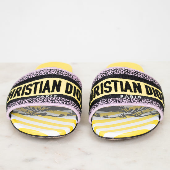 Front view of Christian Dior woven strap slides with yellow and  black  with white striped pattern on a white and marble background