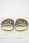 Front view of Christian Dior woven strap slides with yellow and  black  with white striped pattern on a white and marble background