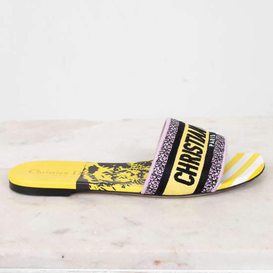 Side view of Christian Dior slides with yellow and  black  with white striped pattern on a white and marble background