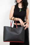 Person holding a black handbag with red accents against a white background
