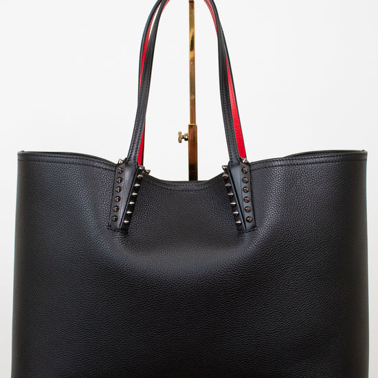 Black leather tote bag with red accents and gold spike accents on handle on a white background