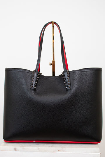 Black leather tote bag with red accents and gold spike accents on handle on a white background