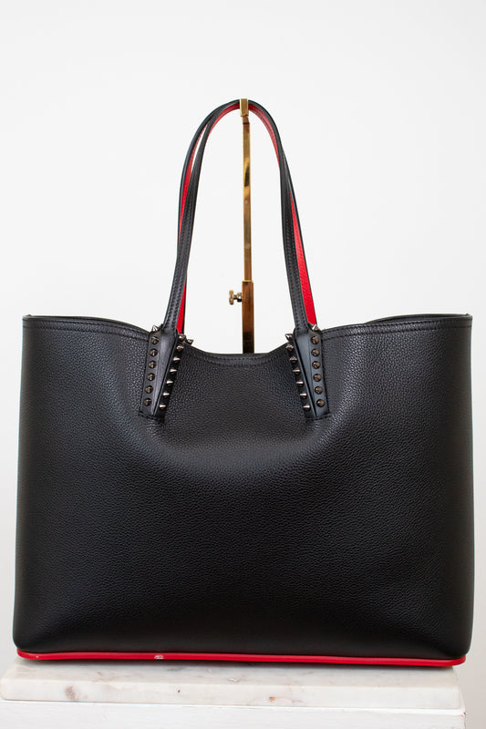 Black leather tote bag with red accents and gold spike accents on handle on a white background