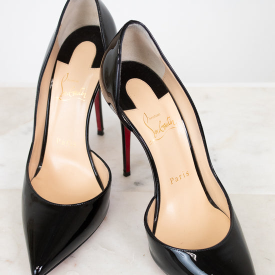 Black high-heeled shoes with red soles on a white background