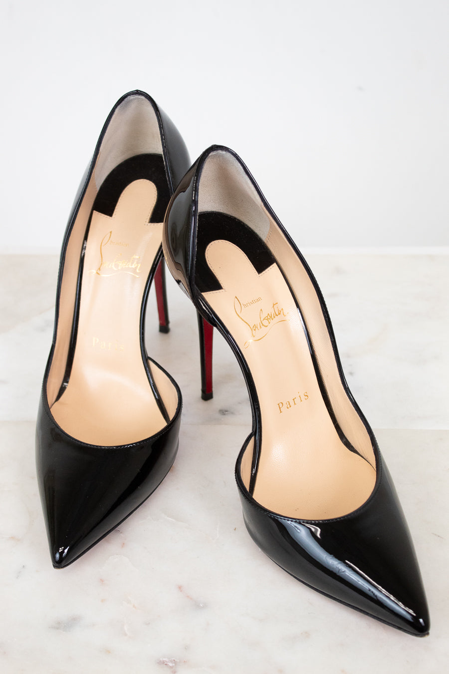 Black high-heeled shoes with red soles on a white background