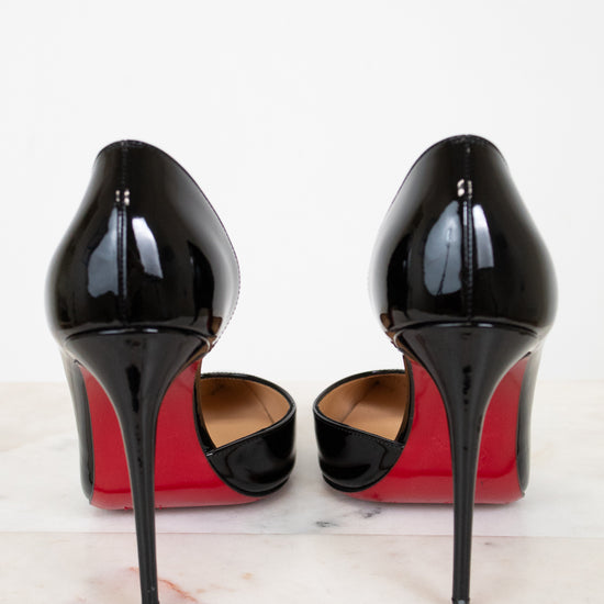 Black high-heeled shoes with red soles on a white background