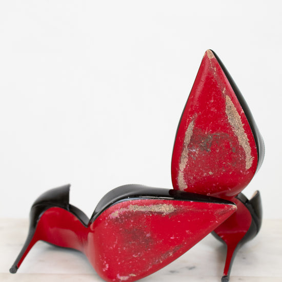 Black high-heeled shoes with red soles on a white background