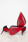 Black high-heeled shoes with red soles on a white background