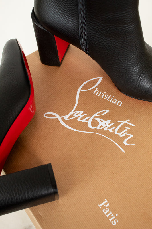 Black and red high-heeled shoes on a brown box with 'Christian Louboutin' branding.