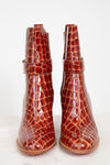 Pair of brown crocodile-patterned boots on a white background