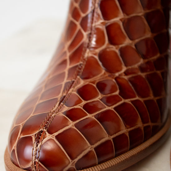Close-up of a brown leather shoe with intricate pattern on a light background