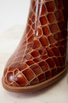 Close-up of a brown leather shoe with intricate pattern on a light background